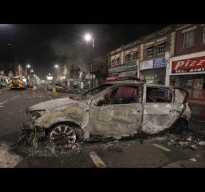 A burnt police car is seen on a street in Tottenham