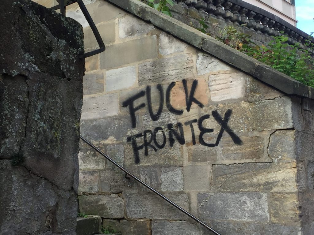 Graffiti on a wall reads 'FUCK FRONTEX'