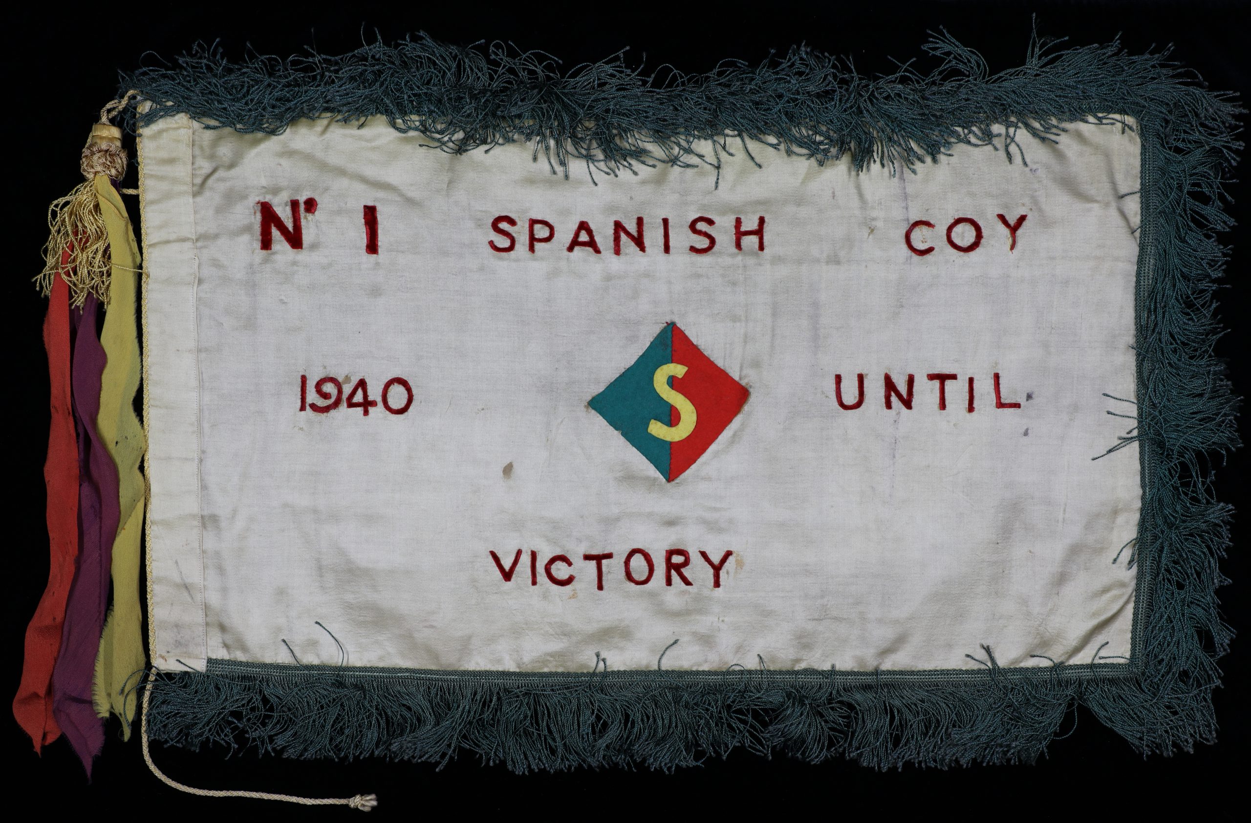 A cloth banner with coloured tassels reading No 1 Spanish coy 1940 until victory