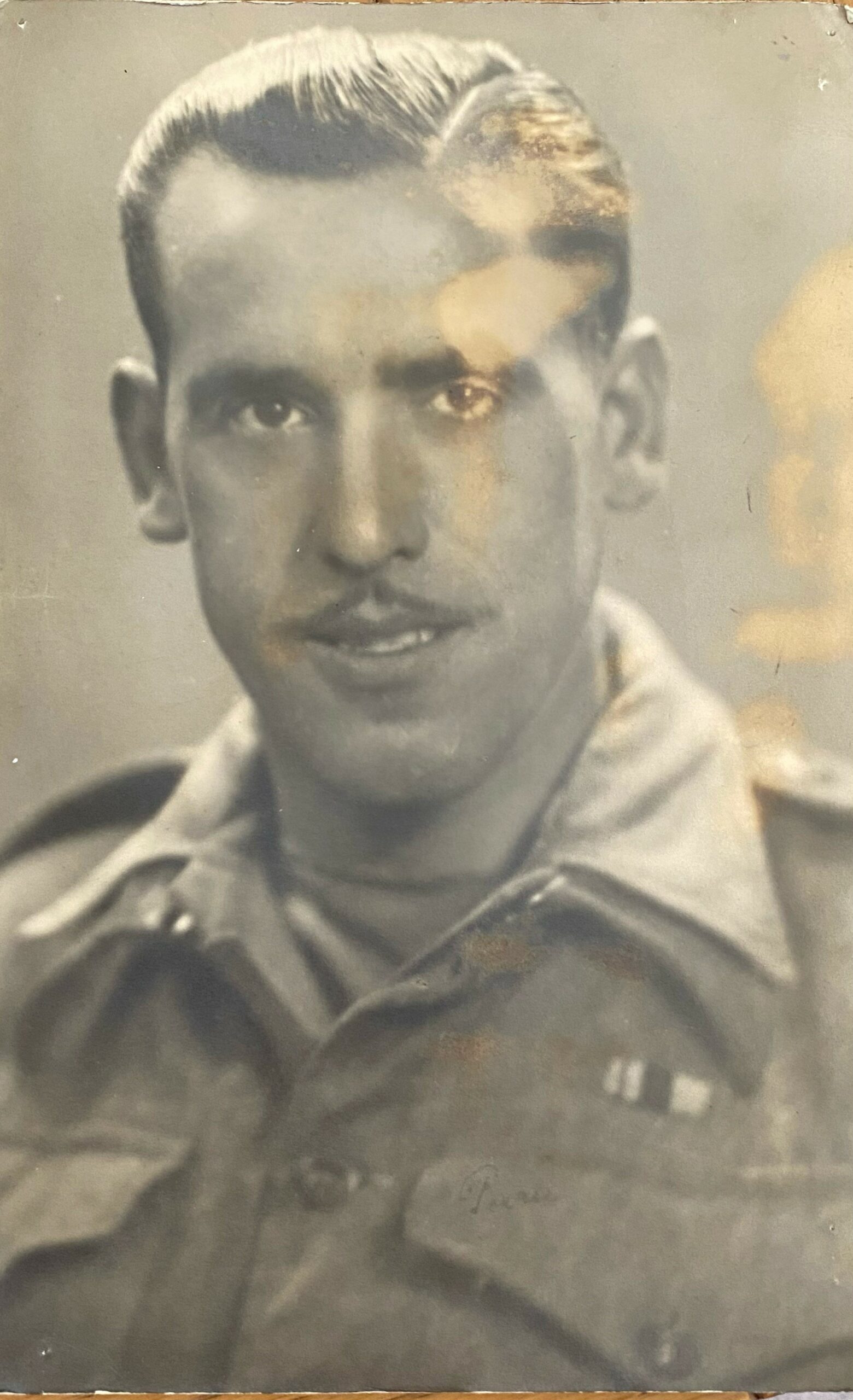 Old photo of young man in military uniform with slicked back hair and thin moustache