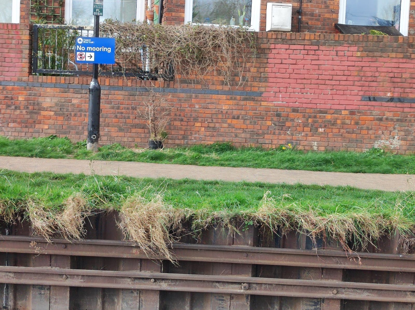 A photograph of the canal bank with a 'No mooring' sign